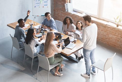 Lektor vede školení malé skupiny u stolu ve workshopové místnosti